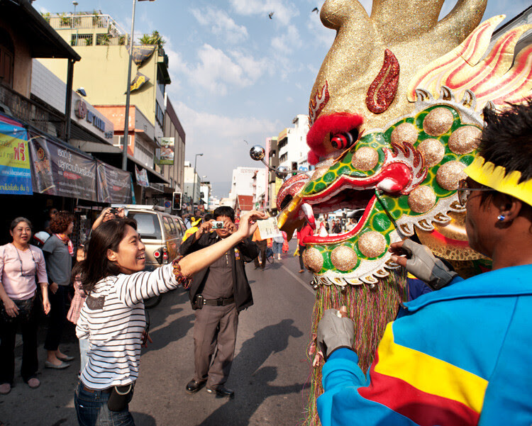 A woman places money in the mouth of a Chinese New Year dragon during a street parade in Chiang Mai, Thailand. - How to be Better Prepared for Your Next Photo Shoot