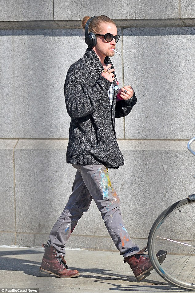 Unique style: The former child star sported a 'grandpa'-style sweater over a chequered shirt and paint splattered jeans