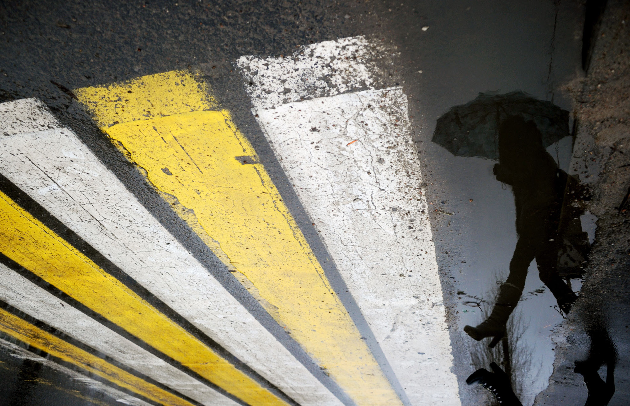 A woman is reflected in a puddle as she crosses a road in Minsk, during warm winter weather 