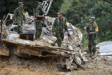 Soldiers stand on the remains of a bus after it was buried by a mountain landslide in Altotonga in Veracruz state, along Mexico's Gulf coast, September 16, 2013. REUTERS-Oscar Martinez
