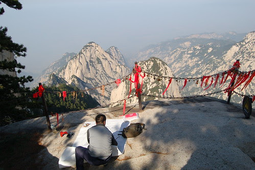 In der Nähe des Westgipfels vom Hua Shan richtet ein Maler seine Papier aus. Die roten Schleifen sind an Vorhängeschlössern angebracht und sollen den Besuchern Glück bringen