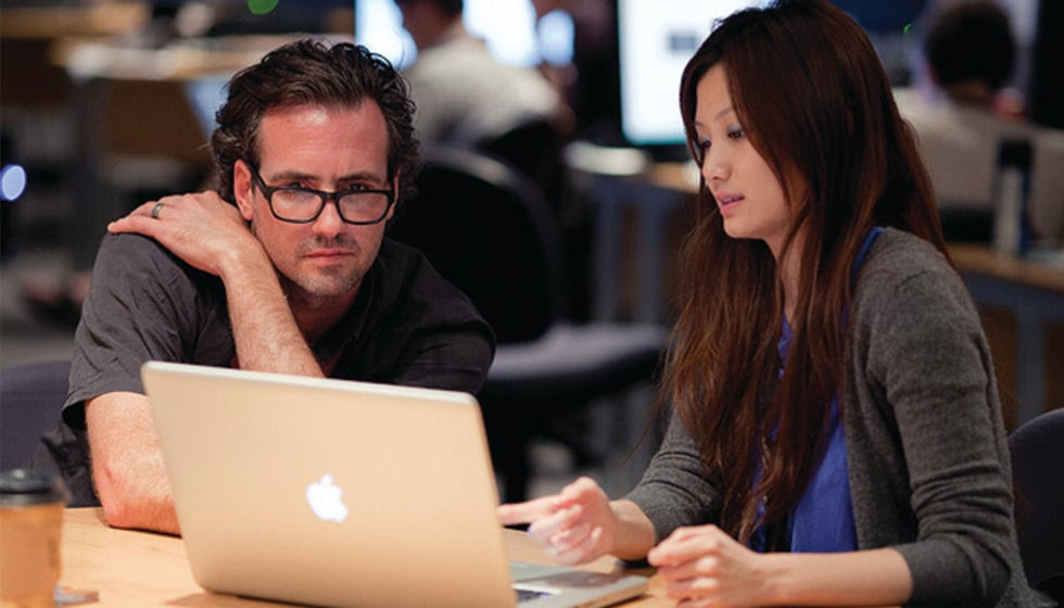 Image of a man and a woman looking at a macbook.
