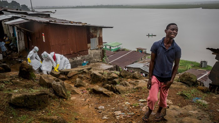 Eric Gweah, 25, grieves as he watches members of a Red Cross burial team carry the body of his father, Ofori Gweah, 62, a suspected Ebola victim, in a riverside area called Rock Spring Valley in central Monrovia, Liberia.