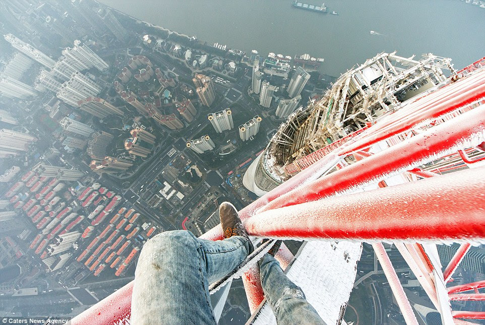 Terrfying: As can be seen in this and the following two images taken in Shanghai, China, Ivan Kuznetsov happily climbs buildings in all weather conditions - even ice covered scaffolding in the dead of winter