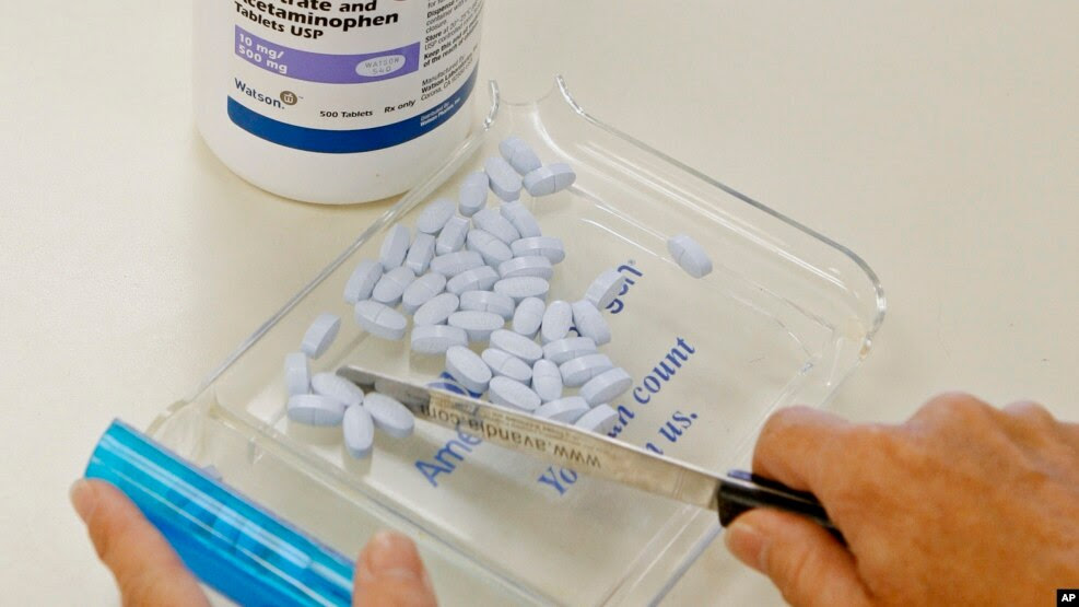 FILE- A pharmacy tech poses for a picture with pills of the generic version of Vicodin, in Edmond, Okla. The U.S. Centers for Disease Control and Prevention says not only do pain medications run a high risk of addicting the user, but they can actually make patients' chronic pain worse. 