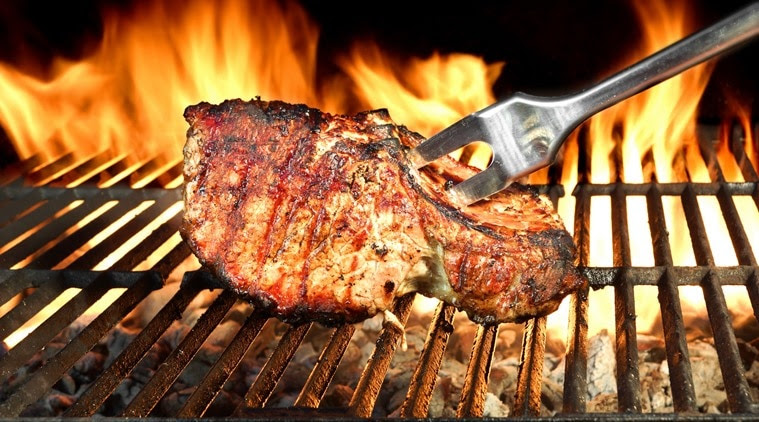 Meat Chop Cooked On The Barbecue Grill. Flame Of Fire In The Background.