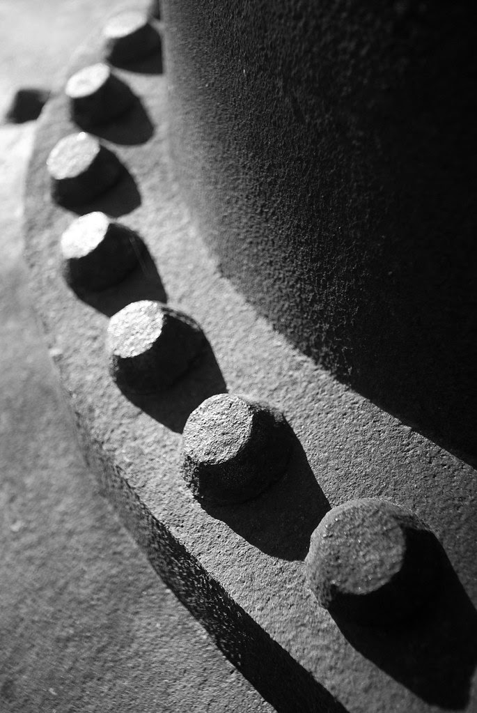 An abstract black and white composition of light and shadows on steel rivets.