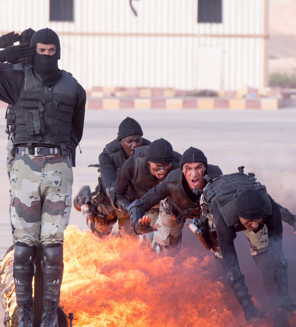 Members of Saudi security forces cross through a fire during a military exercise west of Riyadh, Saudi Arabia