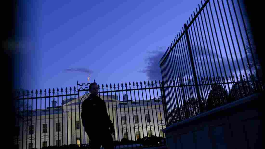 A member of the Secret Service's uniformed division stands by a fence in front of the White House.