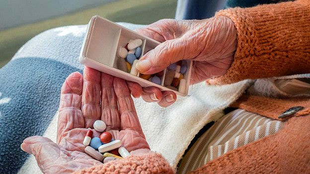 Таблетки в руках у старой женщины