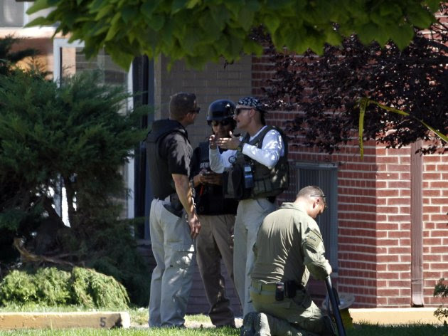 Federal agents outside the apartment of James Holmes in Aurora, Colo., Saturday, July 21, 2012. Federal authorities detonated one small explosive and disarmed another inside Holmes' apartment, but several other explosive devices remained, said Aurora police Sgt. Cassidee Carlson. Twelve people were killed and dozens were injured in a shooting attack early Friday at a packed movie theater during a showing of the Batman movie, "The Dark Knight Rises." Police have identified Holmes, 24, as the suspected shooter. (AP Photo/Ed Andrieski)