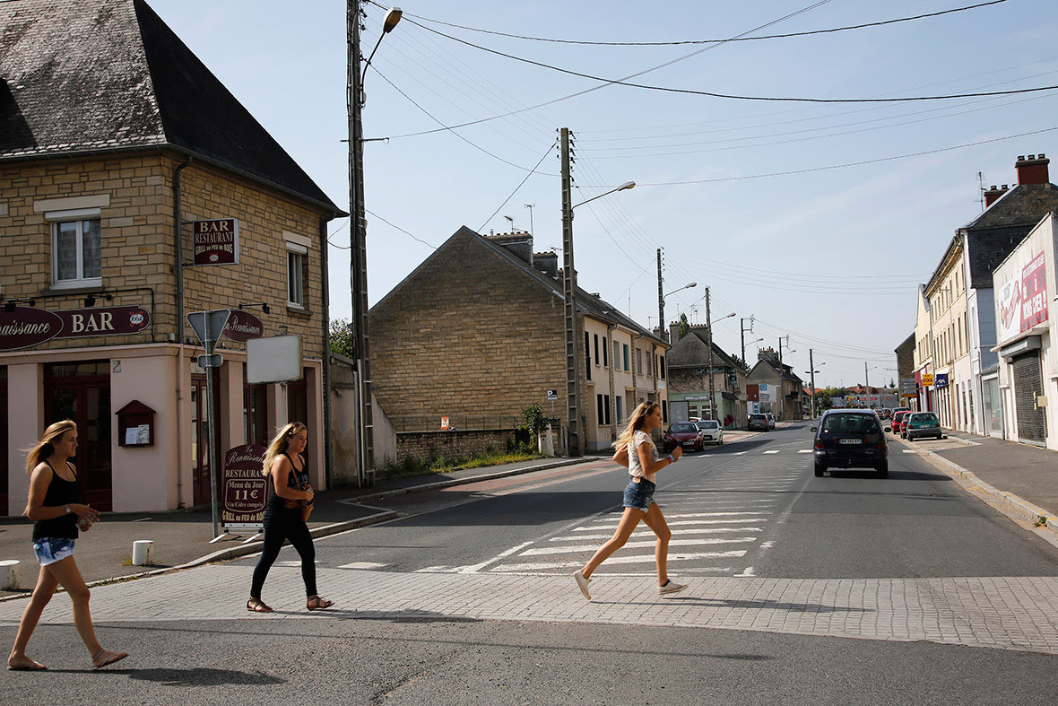 Girls run across the street at the junction of Rue Holgate and RN13 in the Normandy town of Carentan, France