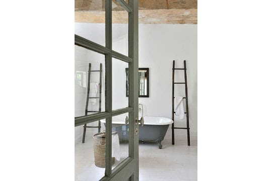 Baignoire ancienne et échelles porte-serviettes en bambou.