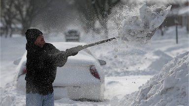 Greg Ledford digs out his Eastpointe. Michigan, side walk after twelve inches of snow on 6 January 2014