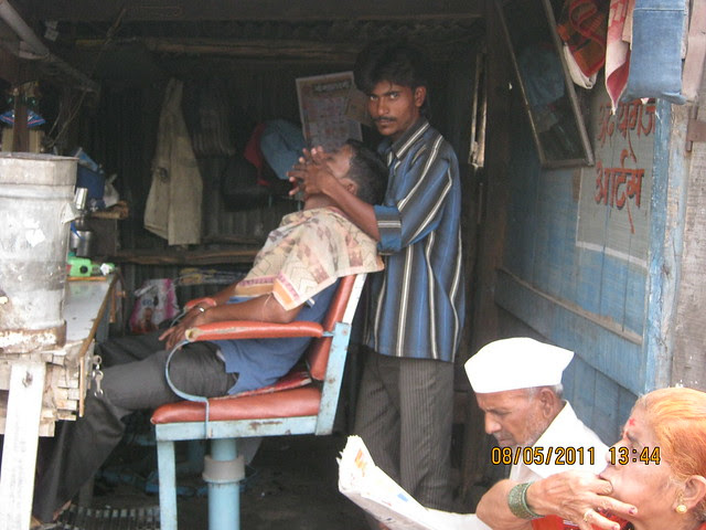While son is having facial for 40 rupees, father & mother are waiting in the road side saloon in Wagholi - annexe of Kharadi - on Nagar Road near Pune