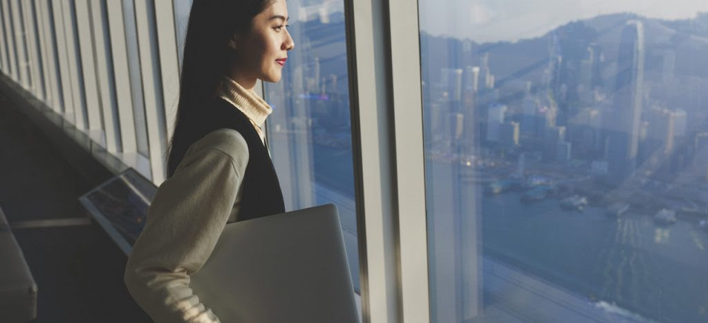 Female entrepreneur looks through a window over a city.