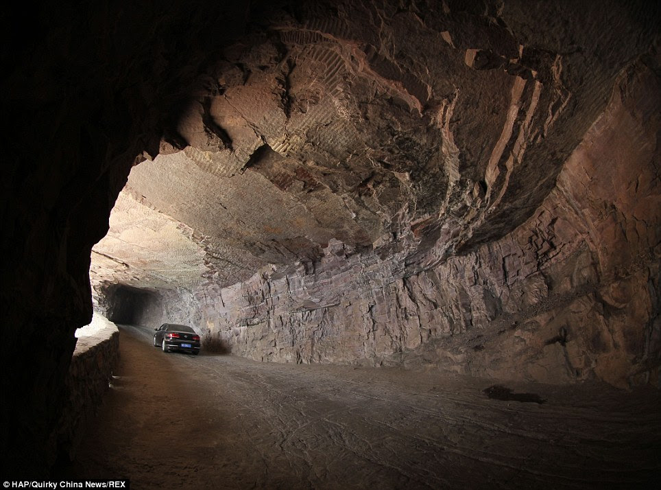 A car makes its way along the cliff corridor which is the only access to the mountainous village in central China