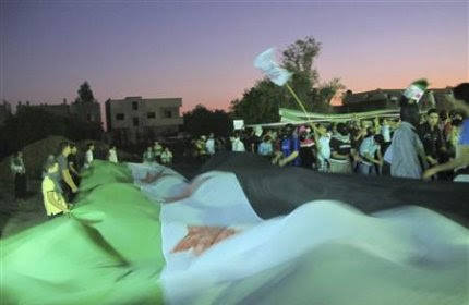 Demonstrators hold opposition flags during a protest against Syria's President Bashar al-Assad at Kfr Suseh area in Damascus