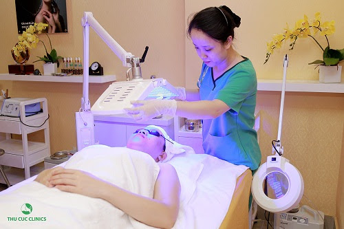 Chuyên viên Thu Cúc Clinics chiếu ánh sáng xanh bằng công nghệ BlueLight sau khi đã làm sạch và lấy nhân mụn cho khách hàng.