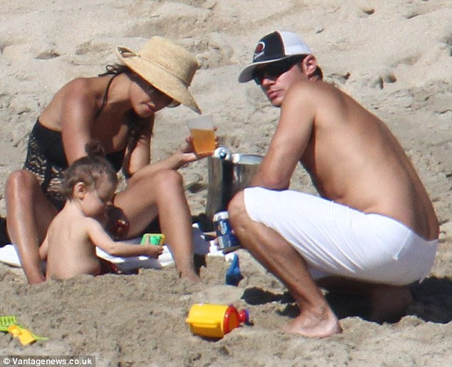Booze the daddy: Nick was supping on a can of beer as he built sandcastles with his baby son Camden