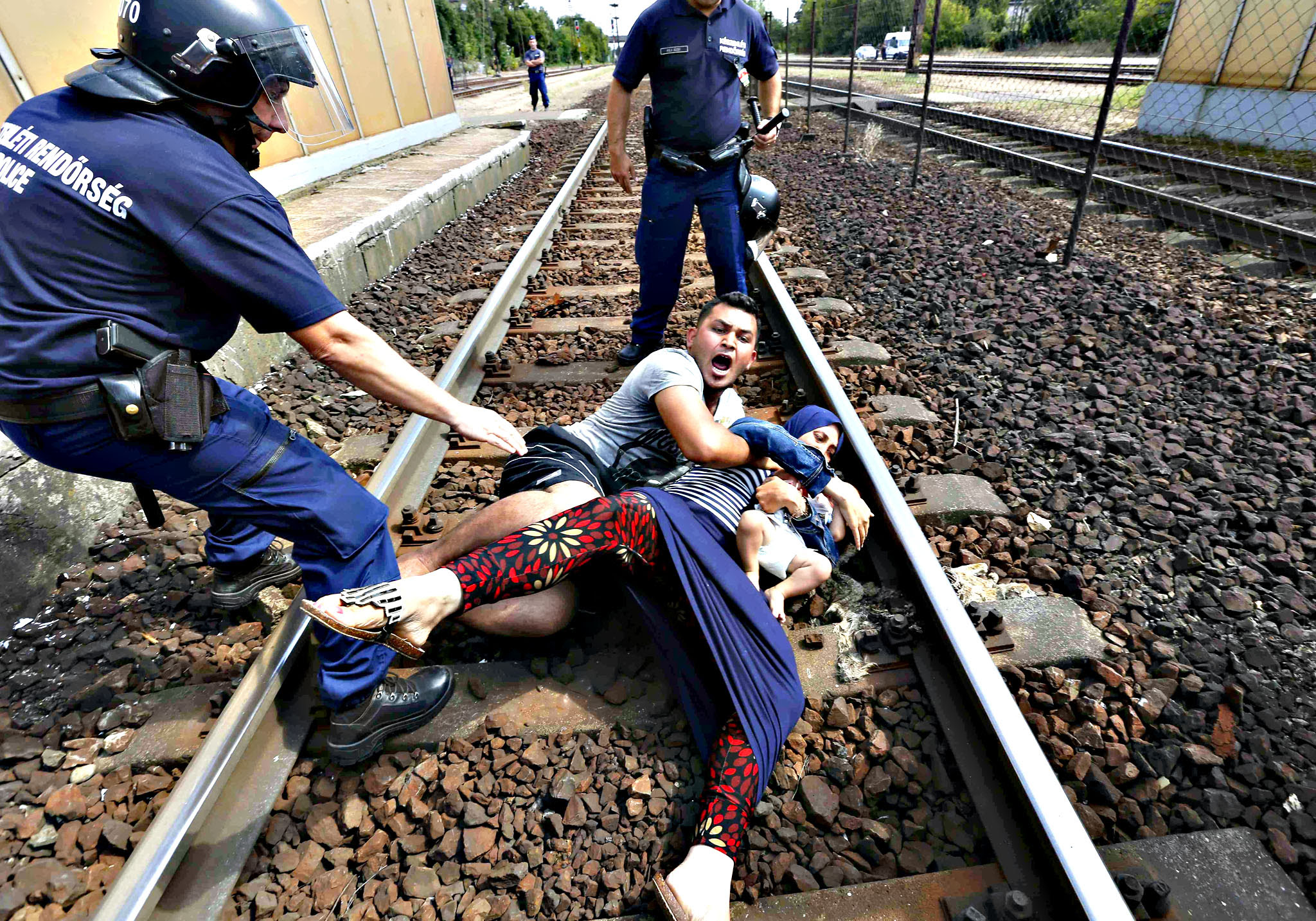 Hungarian policemen stand by the family of migrants protesting on the tracks at the railway station in the town of Bicske, Hungary on Thursday