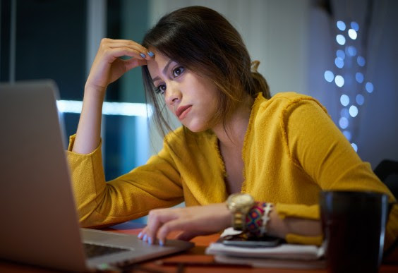A woman looking super stressed at her laptop