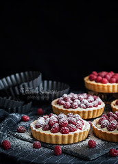 Delicious raspberry mini tarts on dark background