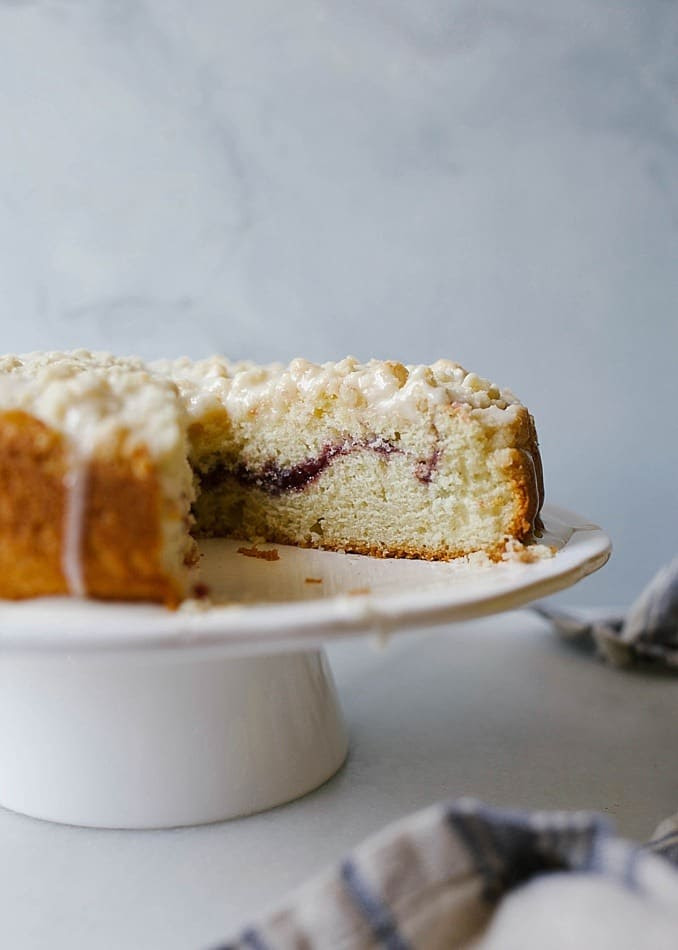 Lemon Berry Crumb Cake recipe by Wood and Spoon blog by Kate Wood. This is a simple lemon zest flavored spring time single layer cake filled with a tart raspberry jam and topped with a simple shortbread crumble. The cake bakes up into an easy dessert that can also serve as a breakfast of brunch item. Pour on a thick powdered sugar lemon glaze for extra decoration. Find the recipe for this Easter favorite on thewoodandspoon.com