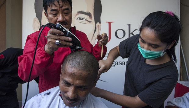 Relawan mencukur rambut seorang sukarelawan untuk merayakan kemenangan ...