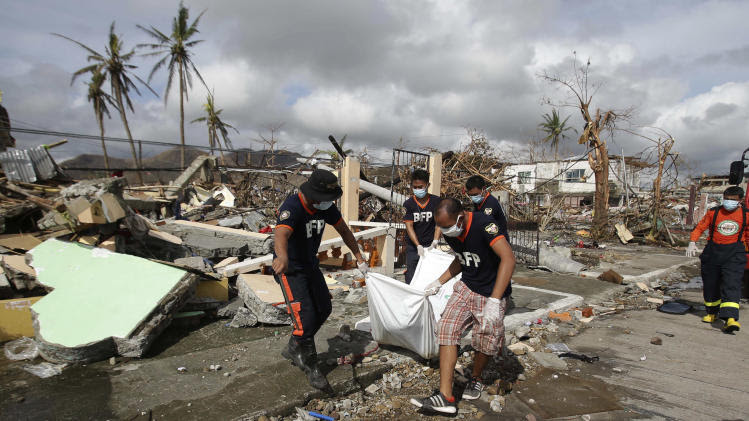 Filipino workers collect dead bodies in typhoon-hit Tacloban city, Leyte province, central Philippines on Wednesday, Nov. 13, 2013. Typhoon Haiyan, one of the strongest storms on record, slammed into six central Philippine islands on Friday leaving a wide swath of destruction. (AP Photo/Aaron Favila)