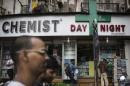 People walk past a chemist shop at a market in Mumbai