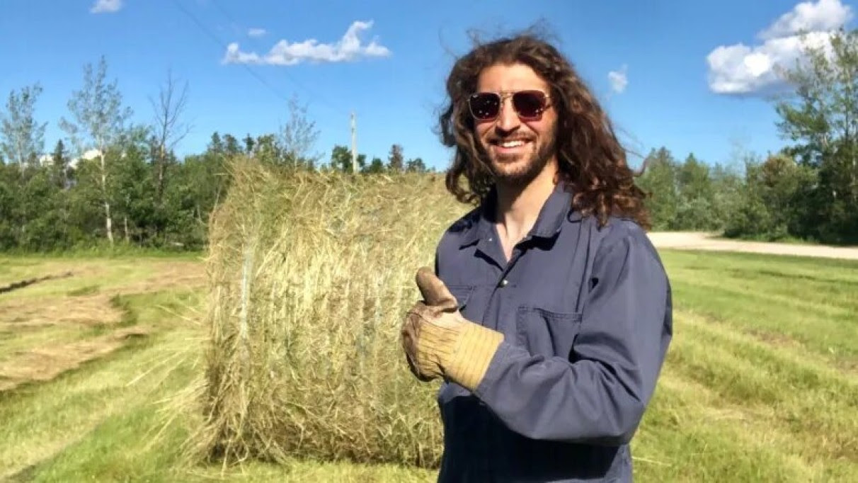 Image description: Jamal Abas standing in front of a haystack on a farm (Jamal Abas/Twitter)