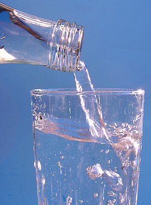 Mineral water being poured from a bottle into ...