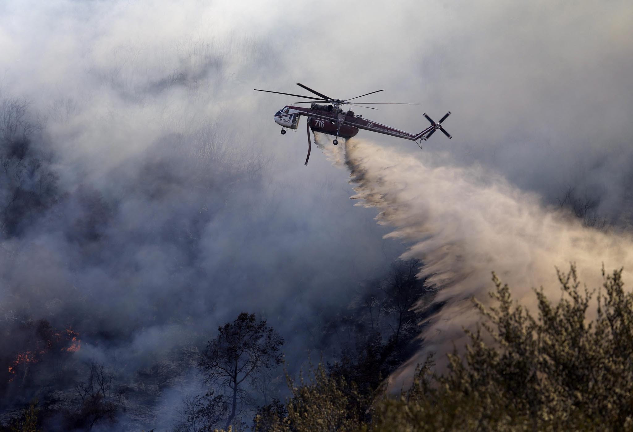 A chopper drops fire retardant on the Blue Cut fire, northeast of Los Angeles, California, USA