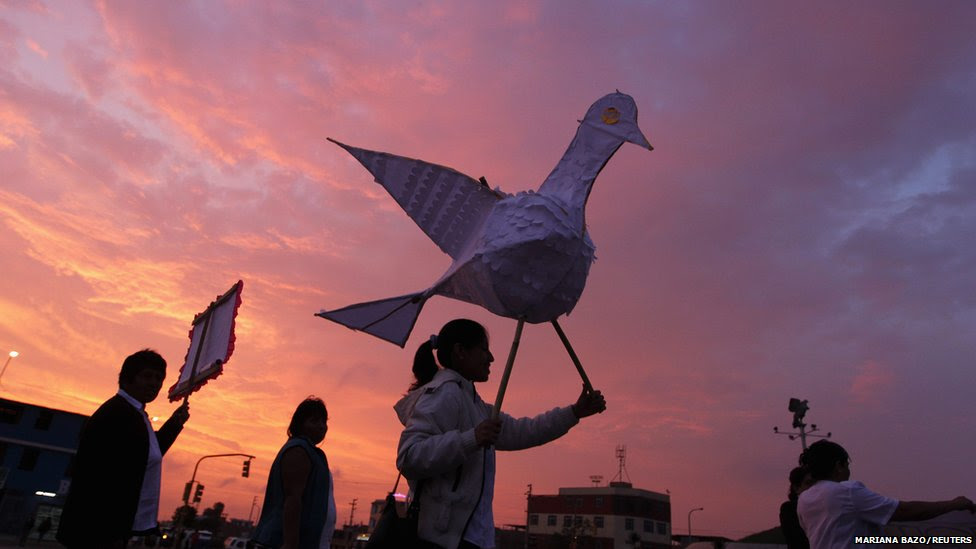 A woman holds up a large paper dove