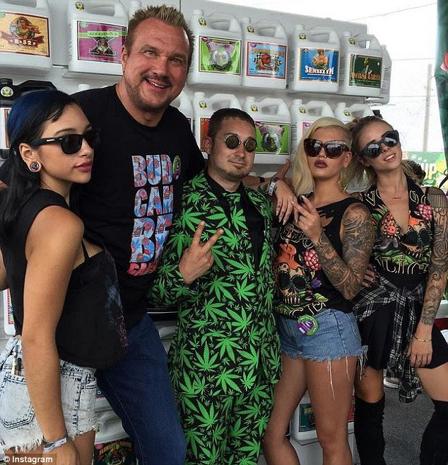 A man wearing a marijuana-themed suit poses for a photo under some of Big Mile's products  