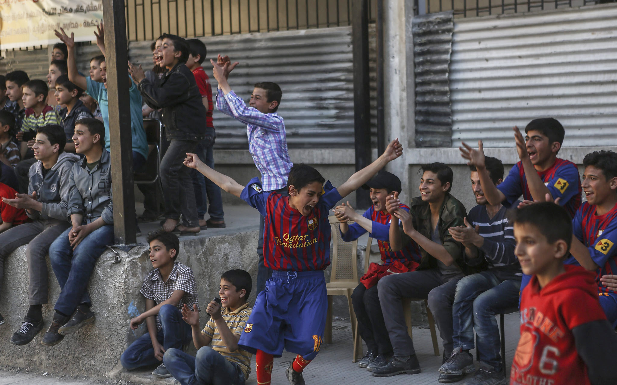 epa05313534 A photograph made available on 18 May 2016 shows substitutes reacting after their team-mates scored a goal during the first school football tournament, in the rebel-held city of Douma, Syria, 20 April 2016. Twelve teams took part in the first school football tournament that started on 16 April 2016. Ten days later the tournament was postponed after the fragile ceasefire between the government and rebel groups was breached by a wave of violence and several parts of Eastern Ghouta were targeted by government shelling. The final match was held on 14 May and al-Hekma school team snatched the title after beating al-Rowad school.  EPA/MOHAMMED BADRA