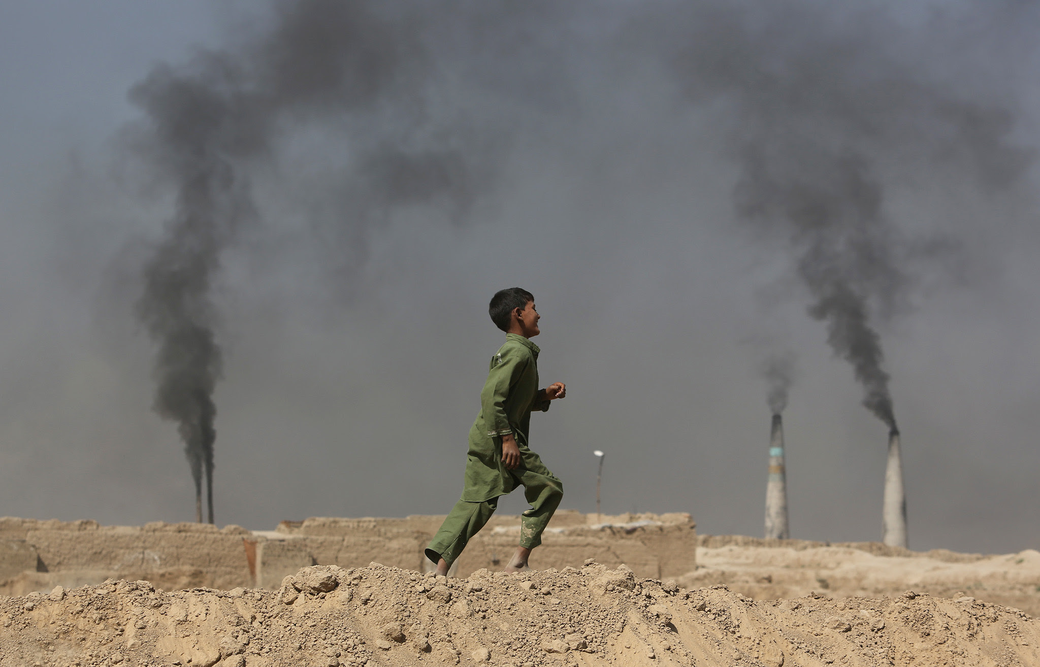 An Afghan boy runs past at a local brick factory on the outskirts of Kabul, Afghanistan, Monday, Sept. 19, 2016. (AP Photo/Rahmat Gul)