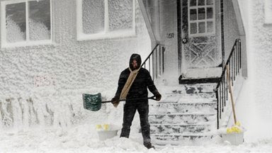 A man sweeps snow from the front of his house in Winthrop, Massachusetts, 9 February