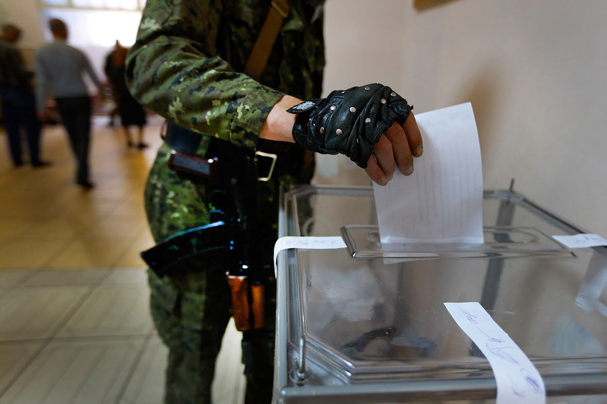 An armed pro-Russia militia casts his ballot at a polling station during a referendum in the eastern Ukrainian city of Slovyansk