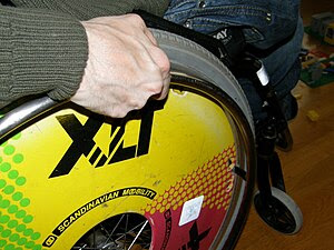A close-up of a rear wheel of a wheelchair.