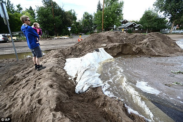 Lucky: Jon Tarkington with his daughter Evy, 1, look over a diversion dam built in the intersection of 7th Street and University Ave on University Hill in Boulder, Colorado on Saturday 