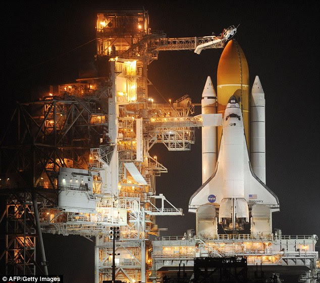 Revealed: Discovery awaits lift-off at Kennedy Space Center in Florida last night after its rotating service structure (left) is moved away