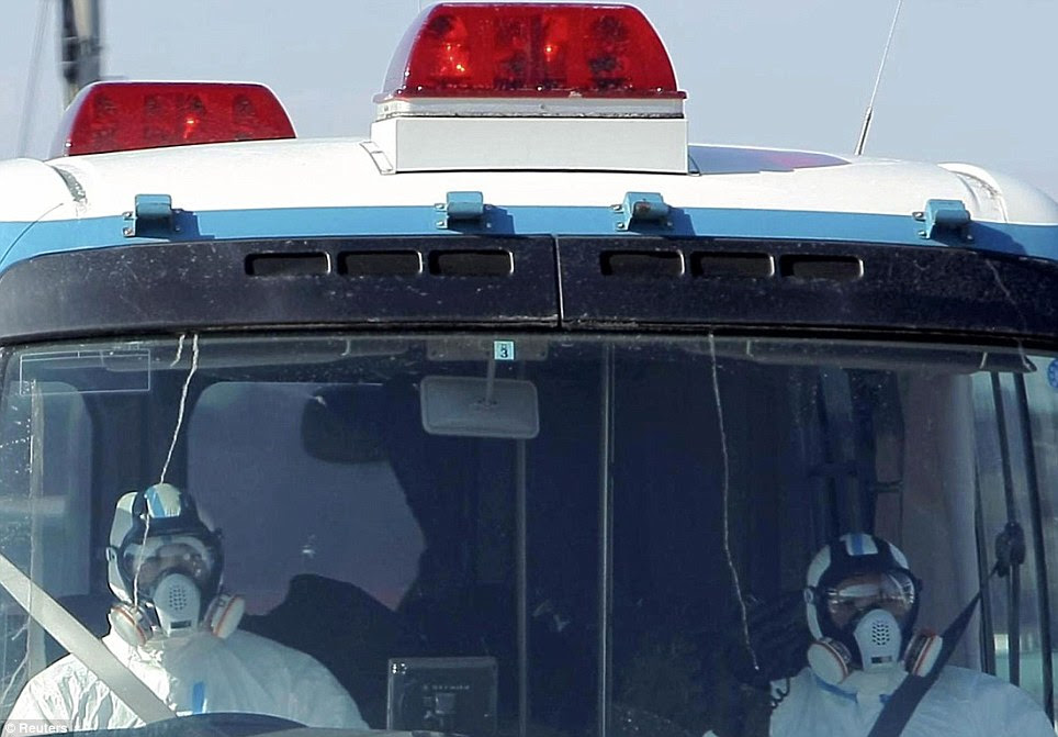 Dangerous work: officials wearing protective clothing and respirators head towards the Fukushima nuclear plant