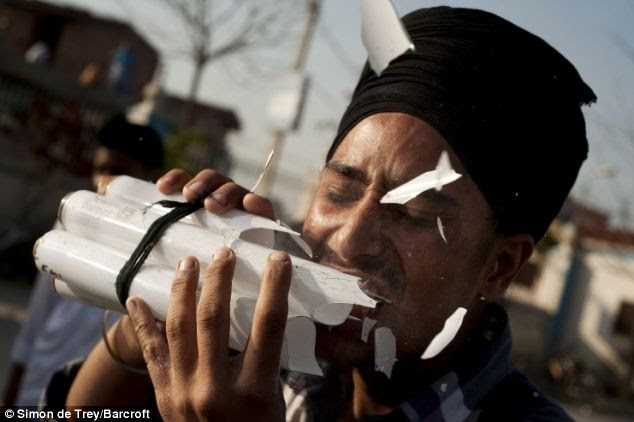 Bright spark: Amandeep Singh, 20, a member of the Bir Khalsa Sikh Martial Arts Group, chews fluorescent strip lights in Amritsar, India