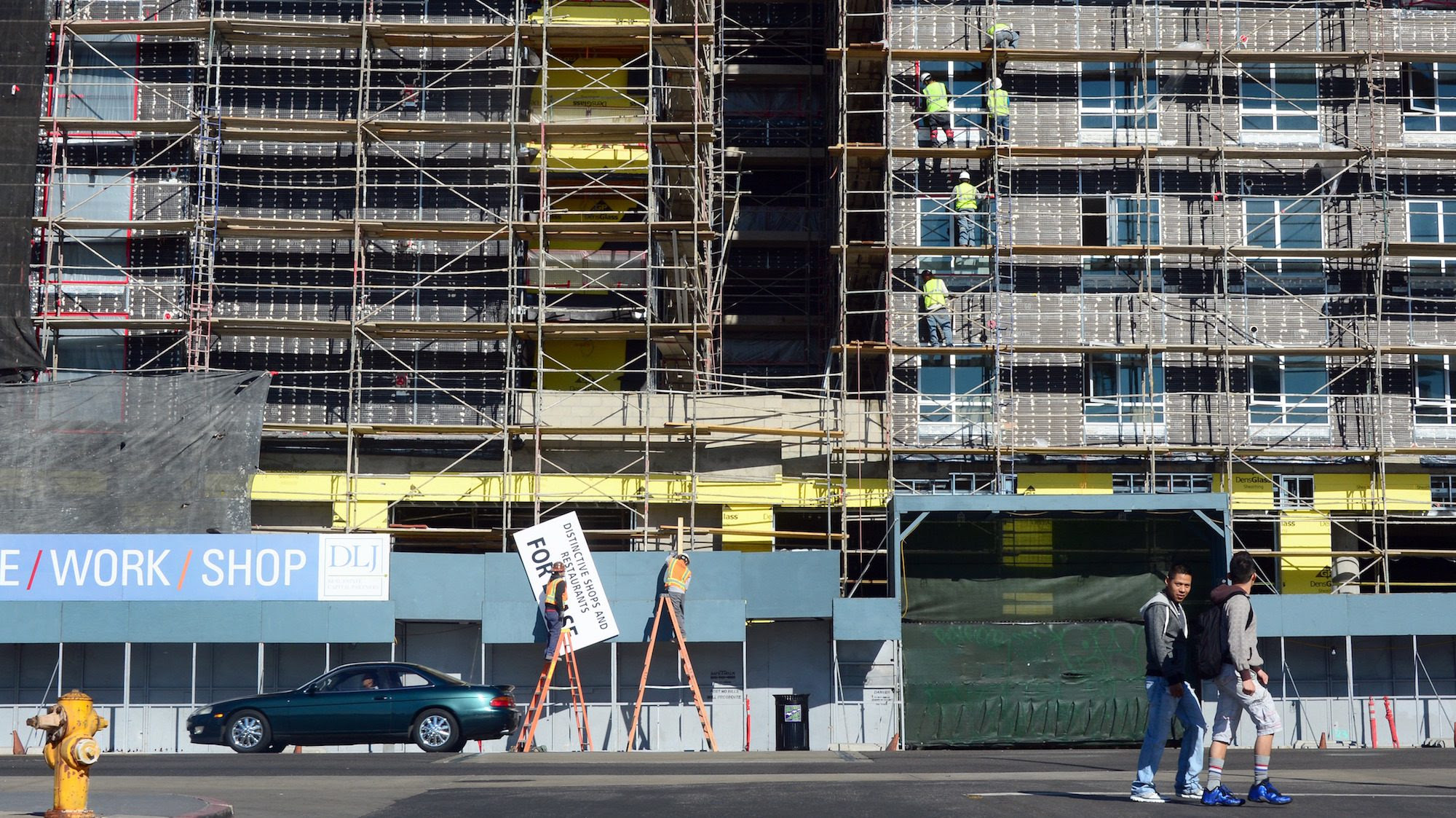 Construction workers are seen on the exterior of a commercial and residential building going up in Hollywood, Calif., in 2014. Coastal metro areas in California between 1980 and 2010 added new housing units at about half the rate of the typical U.S. metro area.