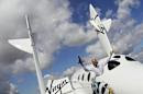 Entrepreneur Branson waves a model of the LauncherOne cargo spacecraft from a window of an actual size model of SpaceShipTwo on display, after Virgin Galactic's LauncherOne announcement and news conference, at the Farnborough Airshow 2012