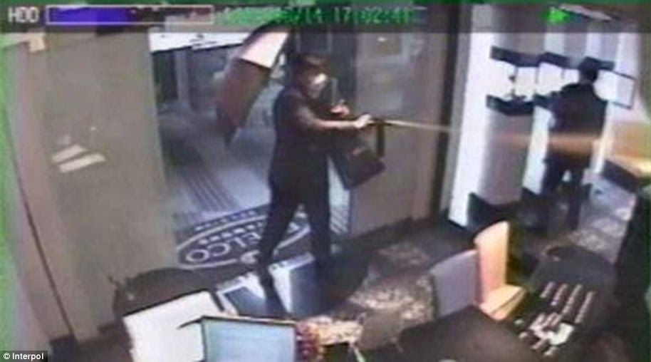 This image released by Interpol shows a member of the gang spraying CS gas at workers in a jewellery shop in Tokyo 