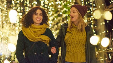 Two women arm and arm next to fairy lights