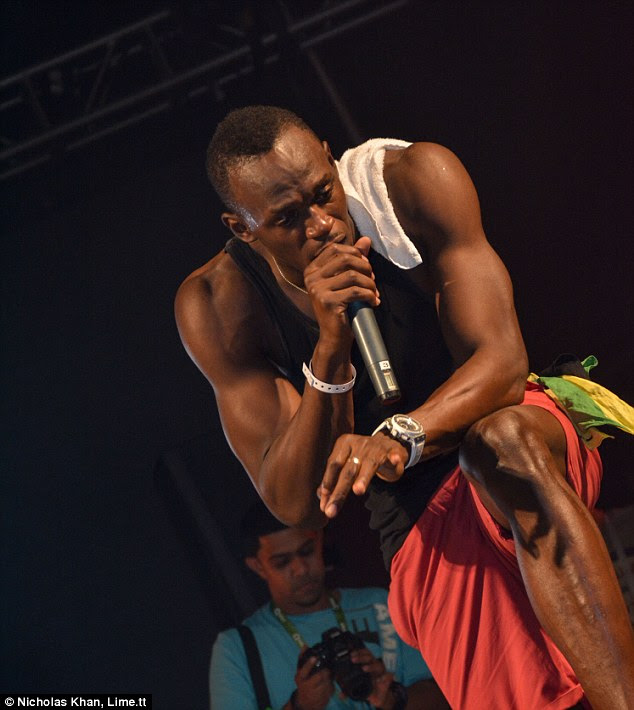 Enjoying his down time: The sprinter showcased his sculpted arms in a black vest top which he teamed with bright orange shorts